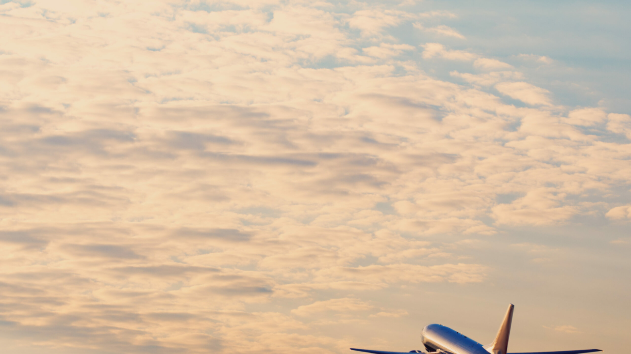 Airplane taking off at the sunset sky, silhouette of aircraft in the sky